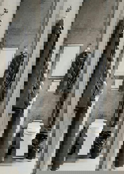 logo Modernt badrum med väggmonterad toalett, betongvägg och två mörka morgonrockar som hänger på krokar