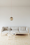 Beige soffa och runt bord på ljust trägolv; hängande lampa ovanför.