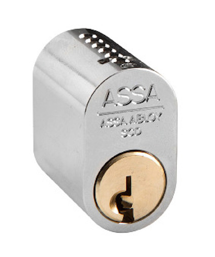 Cylindrisk låskolv i metall med graverad text "ASSA ABLOY" och matt mässingsfärgad kärna.