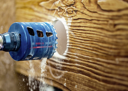 Blå hålsåg borrar i trä, sågspån yr omkring.