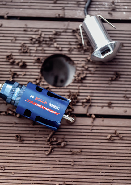 Blå Bosch-hålsåg på träytan med borrade hål och träspån runt om.