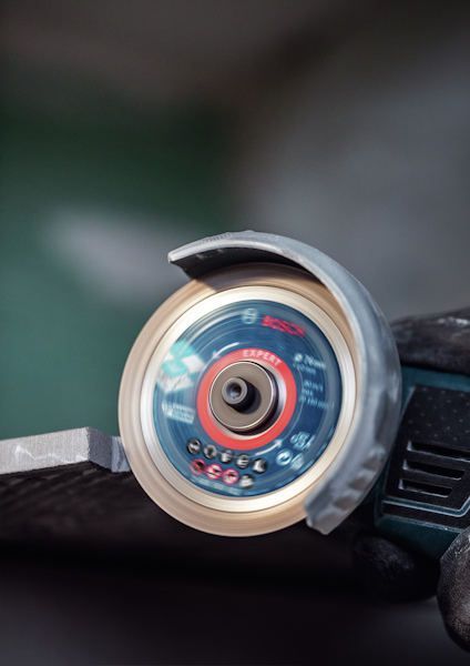 Närbild av en slipmaskin med en roterande diamantklinga, används för att kapa keramiskt material.