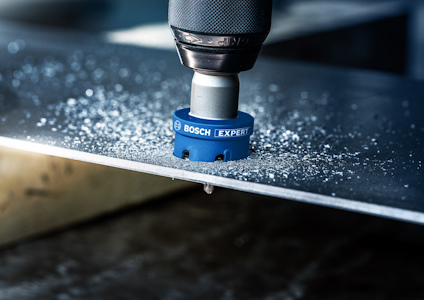 Borr med blått Bosch Expert-borrlock borrar i metallskiva, metallspån på ytan.