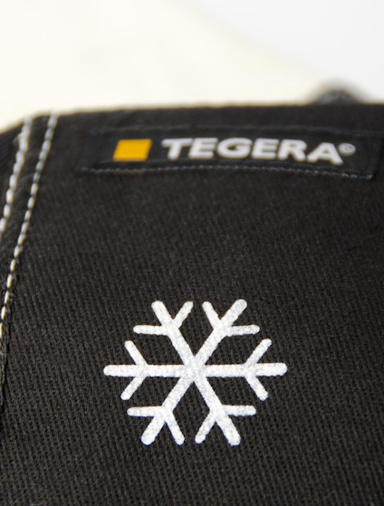 Svart tyg med vit snöflinga och etikett med texten "TEGERA" i vitt och orange.