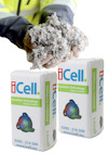Person i gul jacka håller i löst isoleringsmaterial. Framför syns två balar med texten "iCell Insulation Technology Made in Sweden".