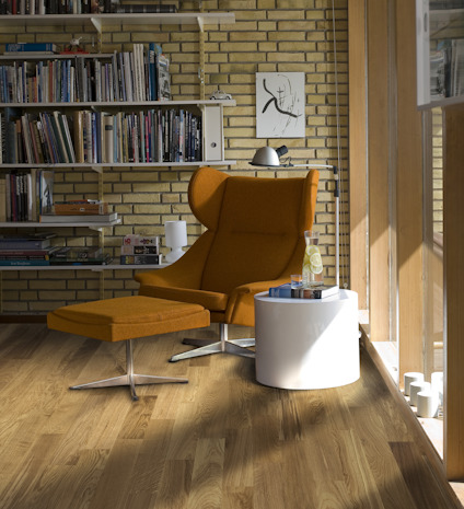 Orange fåtölj och fotpall på trägolv, bredvid ett runt vitt bord med en bok och vattenflaska. Hyllor och konstverk i bakgrunden.