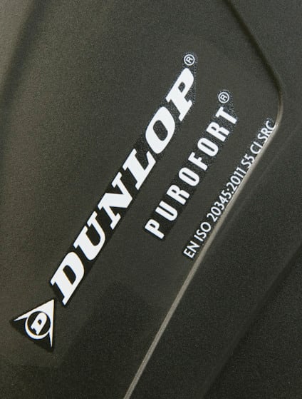 Text på mörk yta: "DUNLOP PUROFORT EN ISO 20345:2011 S5 CI SRC".