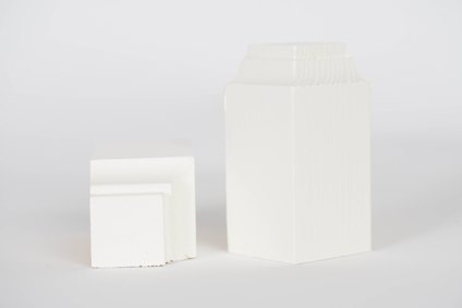 Två vita, stapelbara plastförvaringsbehållare av olika storlekar mot en ljus bakgrund.