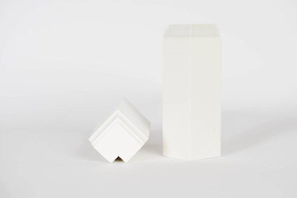 Vita geometriska former; en hög rektangulär prisma och en lutande kub-version bredvid varandra på vit bakgrund.