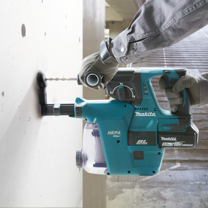 Person borrandes i vägg med blå borrmaskin, text på verktyget: "HEPA", "Makita", "18V".