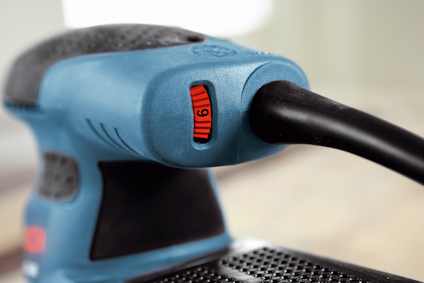 Närbild av slipmaskin med turkos kropp och röd justeringsknapp märkt med siffran "6".