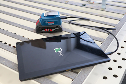 En surfplatta som laddas trådlöst med en Bosch ProCORE18V-batterienhet på randiga ytan.