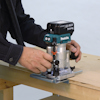 En man använder en Makita-multifräs på ett trästycke.