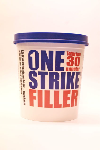 Spackelhink med blått lock, märkning "ONE STRIKE FILLER" i röd och blå text samt "Torkar inom 30 minuter" på framsidan.