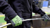 Person med svarta kläder håller i ett metallrör med gröna handskar märkta "TEGERA".