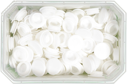 Vit plastlåda fylld med vita, runda plastlock, organiserade oregelbundet.