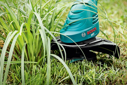 Grästrimmer med Bosch-logotyp klipper gräs.