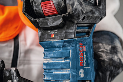 Blå Bosch elverktyg med orange skyddsväst synlig i bakgrunden, närbild av verktygets handtag och knappar.