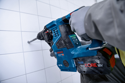 Blå borrmaskin med texten "Bosch ProCORE 18V" borrar i kakelvägg.