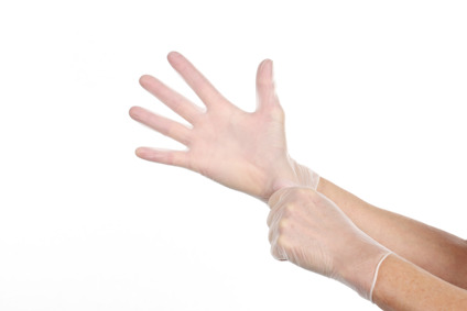 En hand tar på sig ett par tunna, genomskinliga handskar.