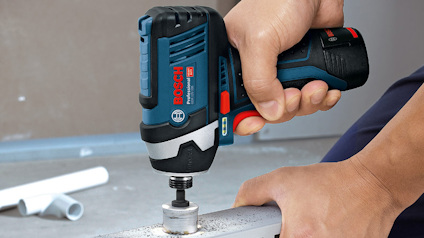 En person använder en Bosch batteridriven borrmaskin för att borra i en metallbalk.