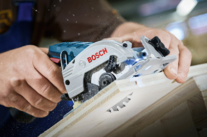 Person sågar trä med en Bosch handhållen cirkelsåg.