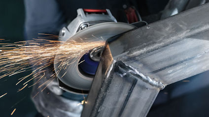 Vinkelslip som skär genom metall, gnistor flyger.