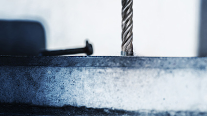 Böjd spik på yta bredvid stålkabel mot suddig bakgrund.