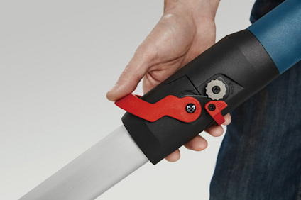 Hand håller i ett verktyg med rött och svart handtag och en blå axel i bakgrunden.