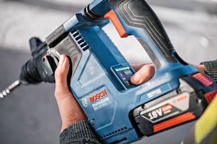 En person håller i en blå Bosch Professional 18V borrmaskin med svarta och orange detaljer.