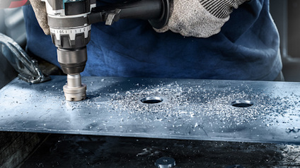 Borrare borrar hål i metallplåt, metallspån sprids runt.