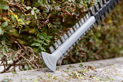 Häcksaxblad som klipper genom en buske med gröna blad.