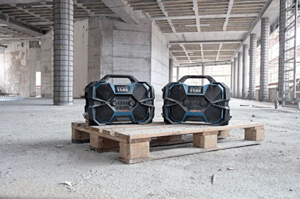 Två svarta och blå verktygslådor sitter på en lastpall i ett ofärdigt industriellt betongutrymme.