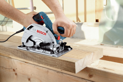 Cirkelsåg från Bosch som sågar en träbräda, hålls av en person.