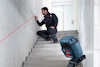 Man justerar röd lasernivå på trappa. Bosch verktyg på stativ.