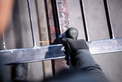 Svartklädd person använder en slangvinda på en metallstruktur utomhus.