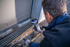 Person inspects a drainage grate and door frame using a handheld inspection camera.