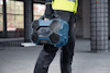 Person i arbetskläder håller en blå Bosch-verktygslåda i industriell miljö.