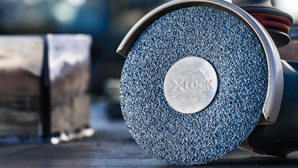 Slipmaskin med blå slippyta och märkningen "X LOCK" i metall på skivan.