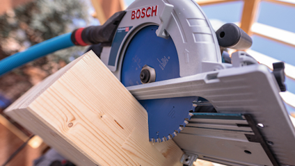 Cirkel-/geringssåg med blått blad och Bosch-logotypen, kapar ett trästycke i en snickarmiljö.