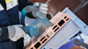 En person i skyddskläder använder en Bosch elektrisk verktyg för att bearbeta tegelblock.
