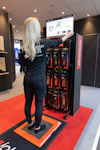 Kvinna står på en digital scanner framför en skärm som visar skoinläggsinformation.