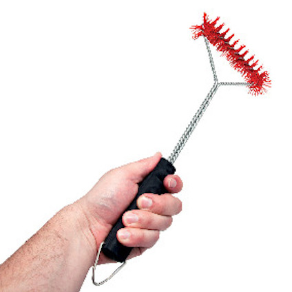Hand som håller en grillborste med röd borste och svart handtag.
