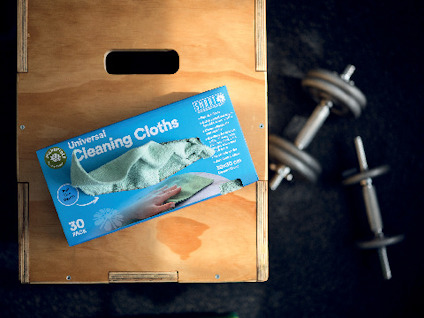 Förpackning med "Universal Cleaning Cloths 30 pack" på en träyta, vikter syns i bakgrunden.