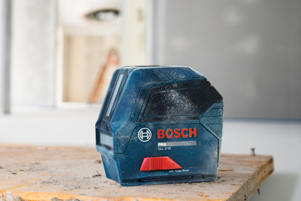 Bosch laseravståndsmätare på träbord med suddig bakgrund.